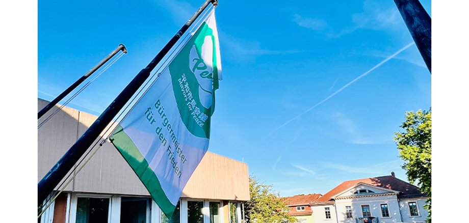 Die Flagge von Mayors for Peace weht vor dem Rathaus der Verbandsgemeinde Nieder-Olm