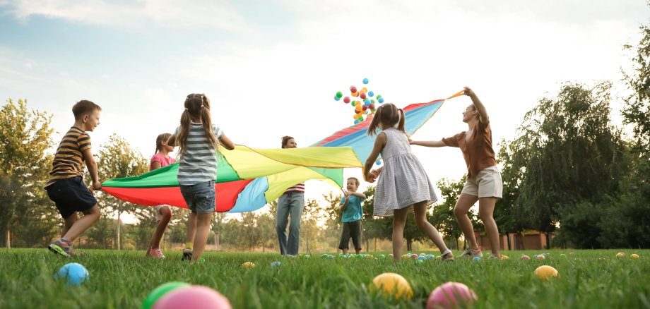 Auf dem Foto sieht man spielende Kinder auf einer grünen Wiese.